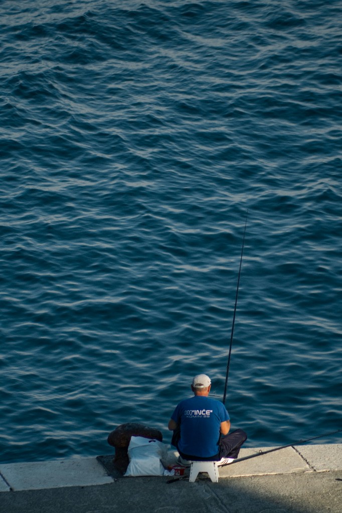 Angler bank fishing beside deep blue water